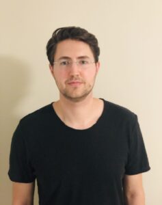 Waist-up shot against a white backdrop of John Kardosh wearing a black shirt.
