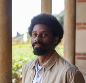 Portrait image of Tory McKinstry wearing a brown jacket in an outside setting.